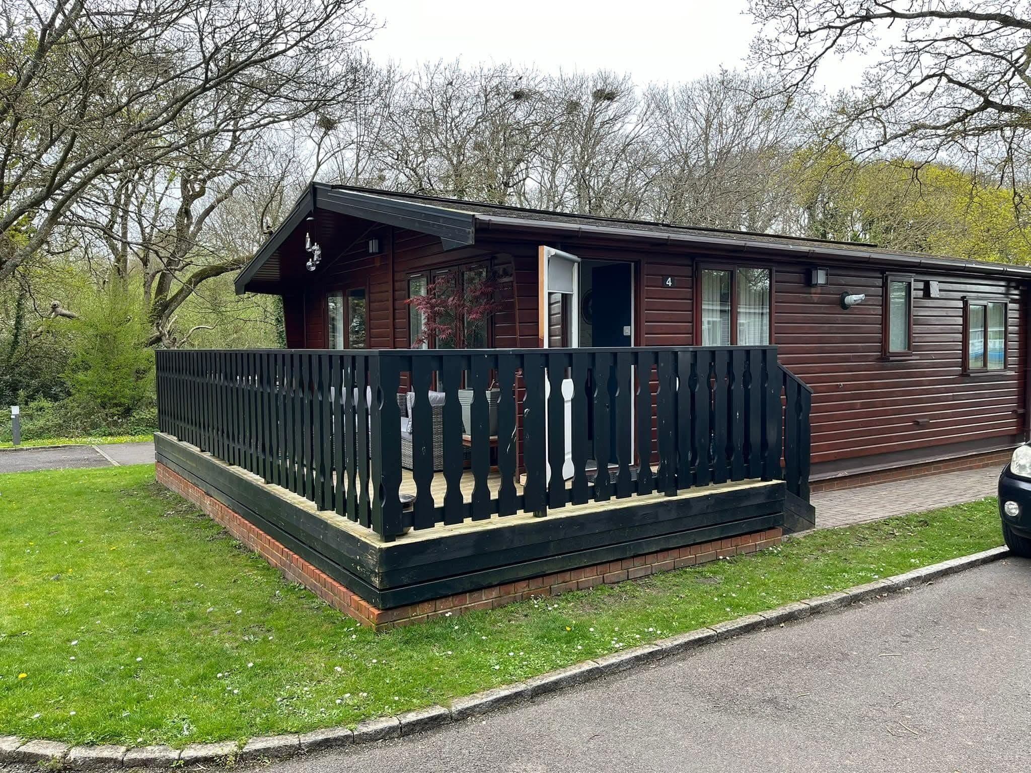 Une cabane en bois avec une véranda et un espace clôturé.