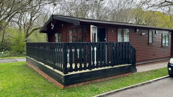 A wooden cabin with a porch and a fenced area.