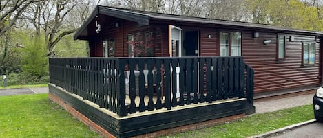A wooden cabin with a porch and a fenced area.