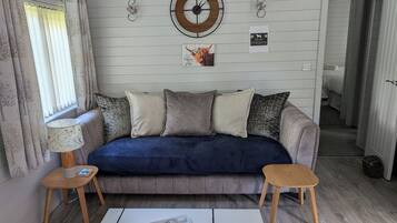 A living room with a sofa, two side tables, a coffee table, and a wall clock.