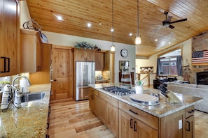 A spacious kitchen with wooden cabinets, a stainless steel refrigerator, and a large island with a built-in stove. - Powder Days & Lake Rays! Tahoe Vista Treasure (Kings Beach)