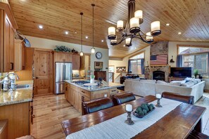 A spacious kitchen with wooden cabinets, a central island, and a dining area with a table and chairs. - Powder Days & Lake Rays! Tahoe Vista Treasure (Kings Beach)