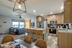 A modern kitchen with wooden cabinets, stainless steel appliances, and a dining area with a table and chairs.
