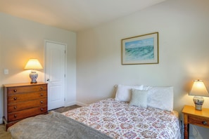 A bedroom with a bed, a dresser, a lamp, and a painting on the wall.