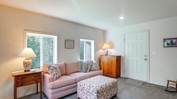 Una habitación con sofá, reposapiés, dos lámparas, un armario y una puerta.