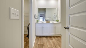A modern bathroom with a vanity, mirror, and a shower area.