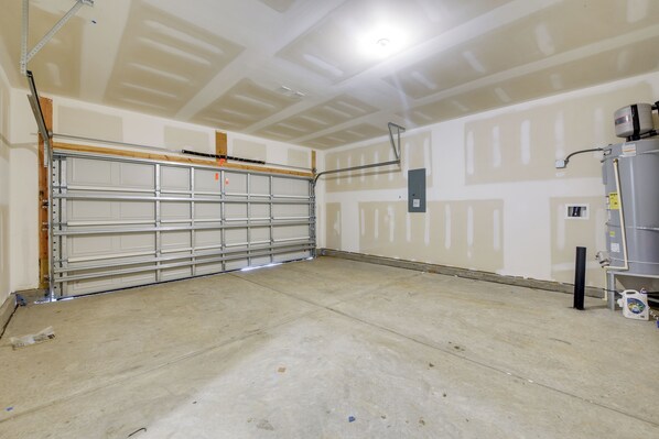 A garage with a closed metal garage door, a water heater, and a concrete floor.