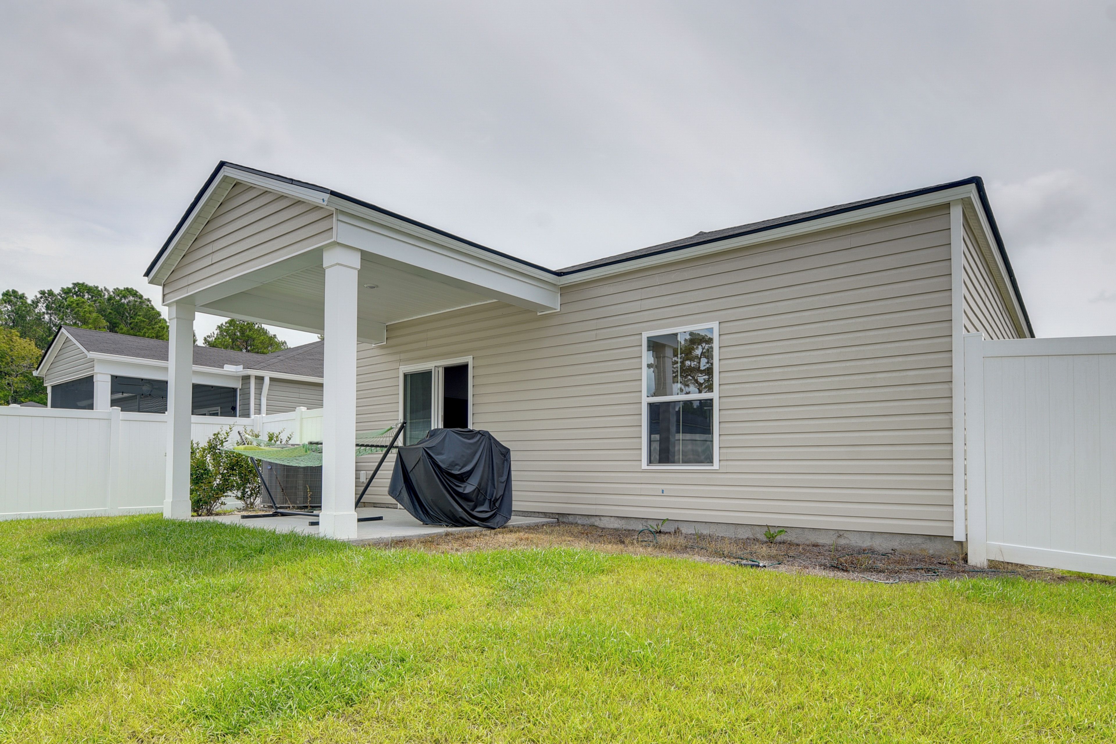 A single-story house with a covered porch, a small window, and a white fence.