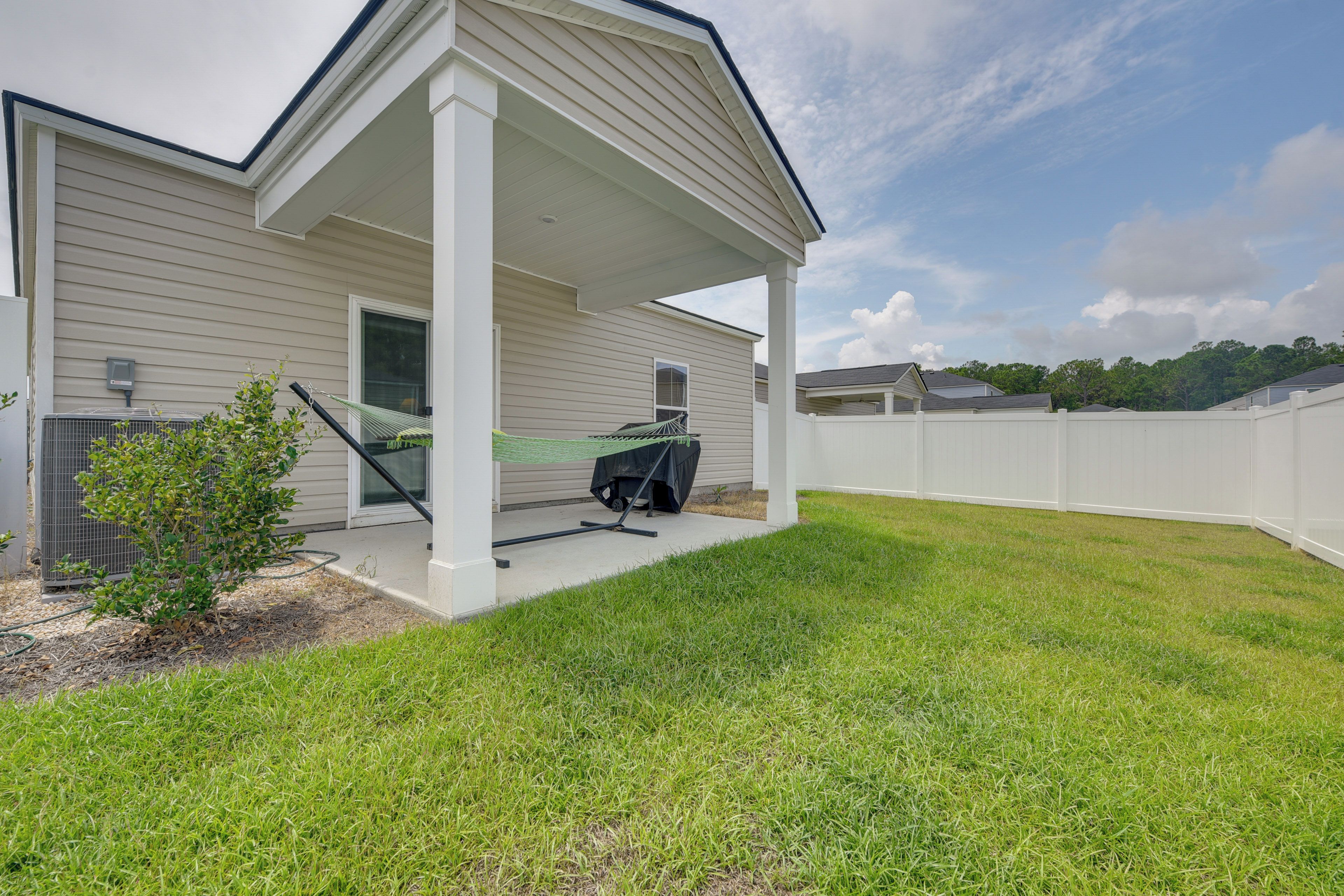 A residential house with a covered porch, a small garden, and a fenced backyard.