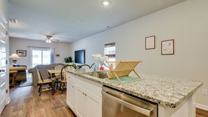 A modern kitchen with a built-in dishwasher, a dining area with a table and chairs, and a ceiling fan.