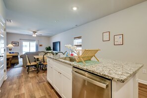 A modern kitchen with a built-in dishwasher, a dining area with a table and chairs, and a ceiling fan.