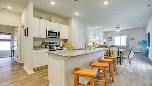 A spacious kitchen with white cabinets, a granite countertop, and a central island with bar stools.