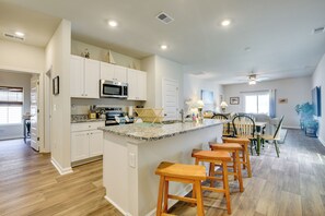 A spacious kitchen with white cabinets, a granite countertop, and a central island with bar stools.
