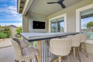 Un patio con una mesa y sillas, un televisor montado en la pared y vista al vecindario.