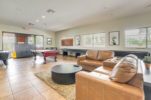 Un área de lounge con mesa de billar, sofás de cuero y mesa de ping pong.