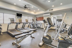 Un gimnasio con cintas de correr, elípticas y equipo de pesas.