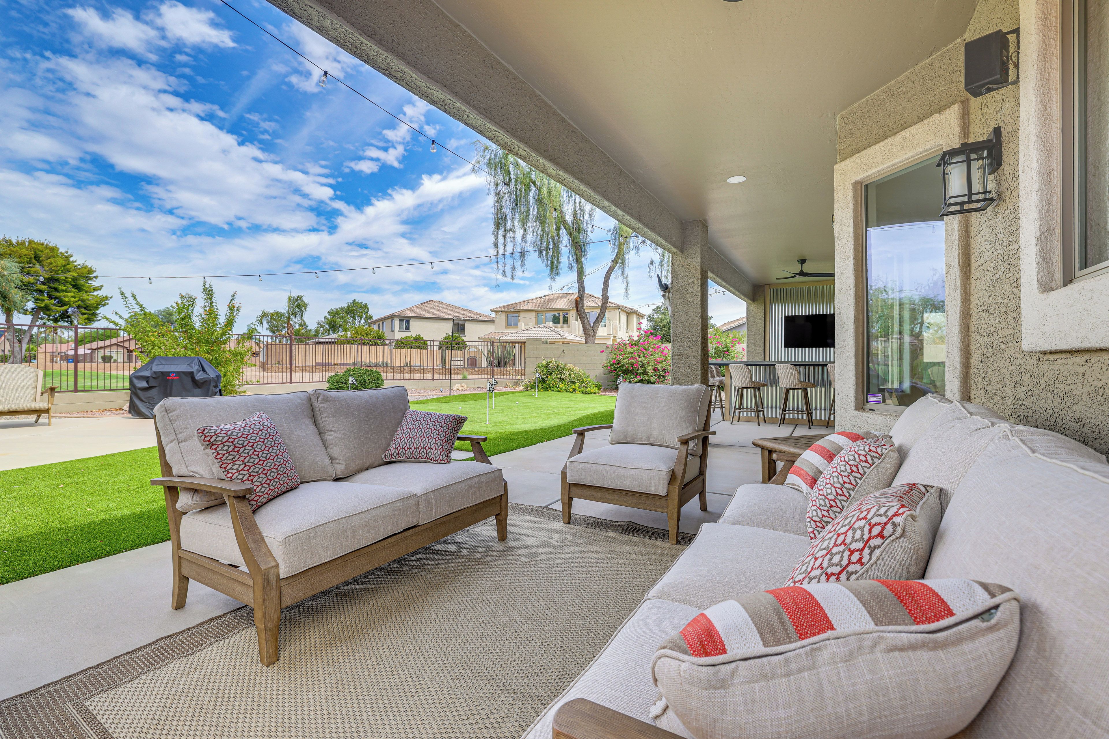 An outdoor patio with a sofa, chairs, and a grill area.