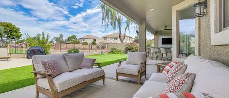 An outdoor patio with a sofa, chairs, and a grill area.
