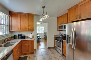 A kitchen with wooden cabinets, stainless steel appliances, and a tiled floor. - Walk to Metro! Historic View Park Home w/ Patio (Los Angeles)