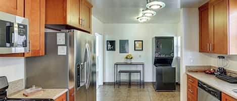 A kitchen with wooden cabinets, stainless steel appliances, a gas stove, a refrigerator, a sink, and a dining area with a table and chairs.