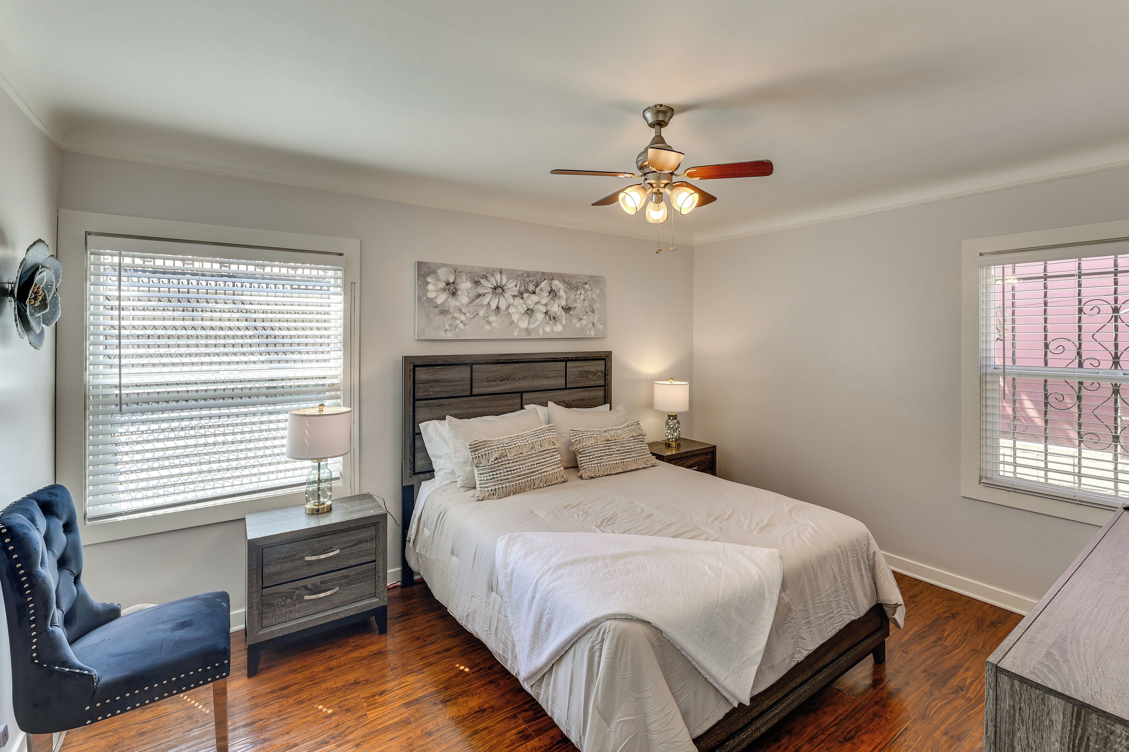 A bedroom with a bed, bedside tables, a chair, and a ceiling fan.
