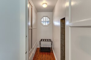 A narrow hallway with a wooden floor, a metal rack, and a hexagonal window. - Walk to Metro! Historic View Park Home w/ Patio (Los Angeles)
