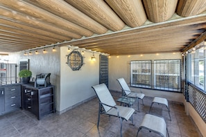A covered outdoor patio with a wooden ceiling, a bar area with a refrigerator, and seating with metal chairs and a glass table. - Walk to Metro! Historic View Park Home w/ Patio (Los Angeles)