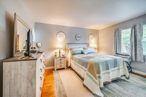 Ein Schlafzimmer mit einem Bett, Nachttischlampen, einem Schminktisch, einem Spiegel und einem Fenster mit Vorhängen.