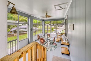 A sunroom with a wooden deck, a round table, and chairs. - Family Beach Retreat w/ Private Pickleball Court (Morehead City)