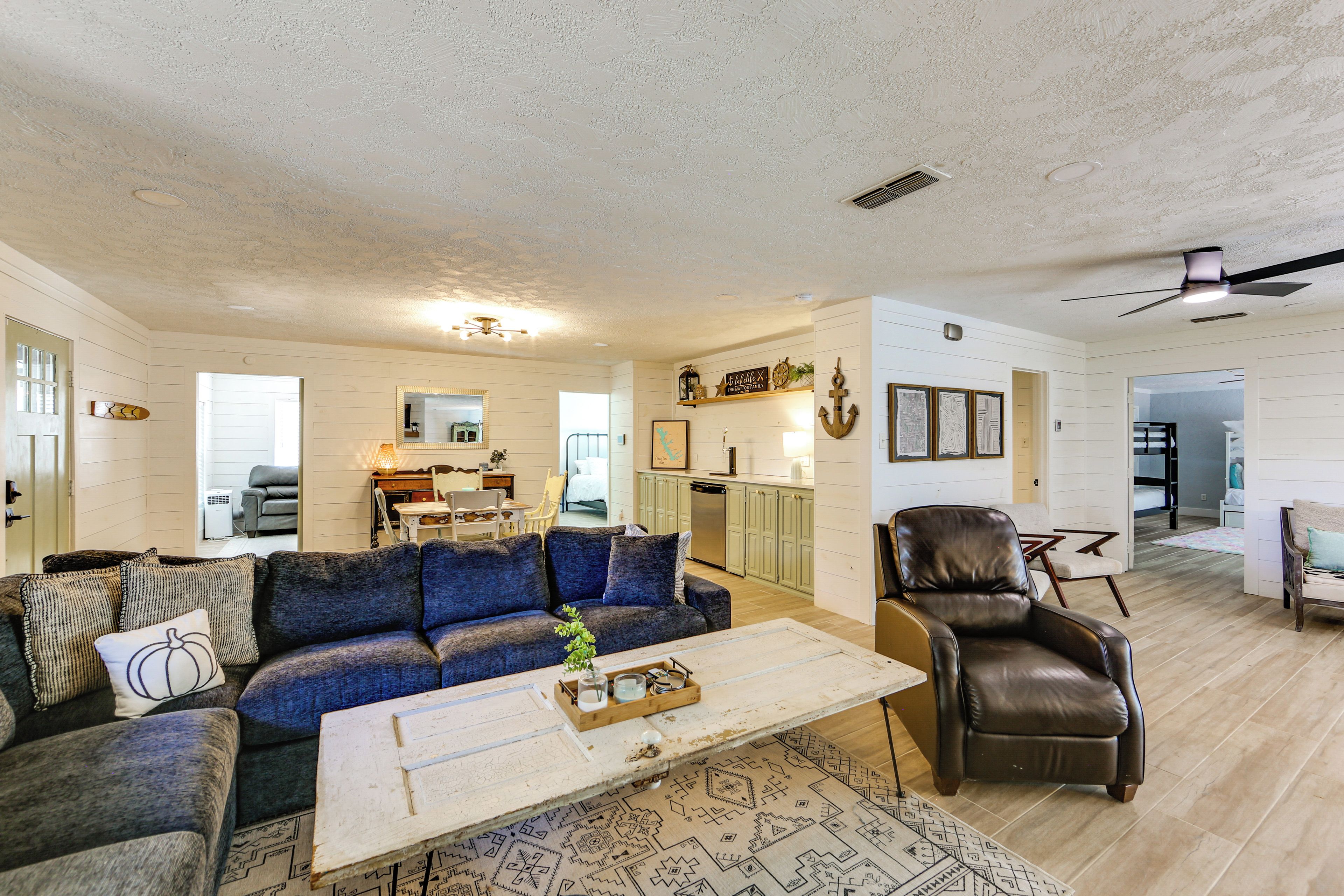 A spacious living room with a blue sofa, a leather armchair, and a coffee table.