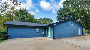 Um edifício azul térreo com garagem, pequeno alpendre e céu limpo.