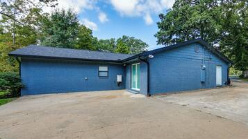 A single-story blue building with a garage, a small front porch, and a clear sky.