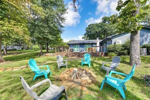 A backyard with a fire pit, outdoor seating, and a house with a deck. - Dock & Golf at Cedar Creek! 'shoreline Retreat' (Malakoff)