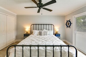 A bedroom with a bed, two bedside tables, a ceiling fan, and a window with blinds.