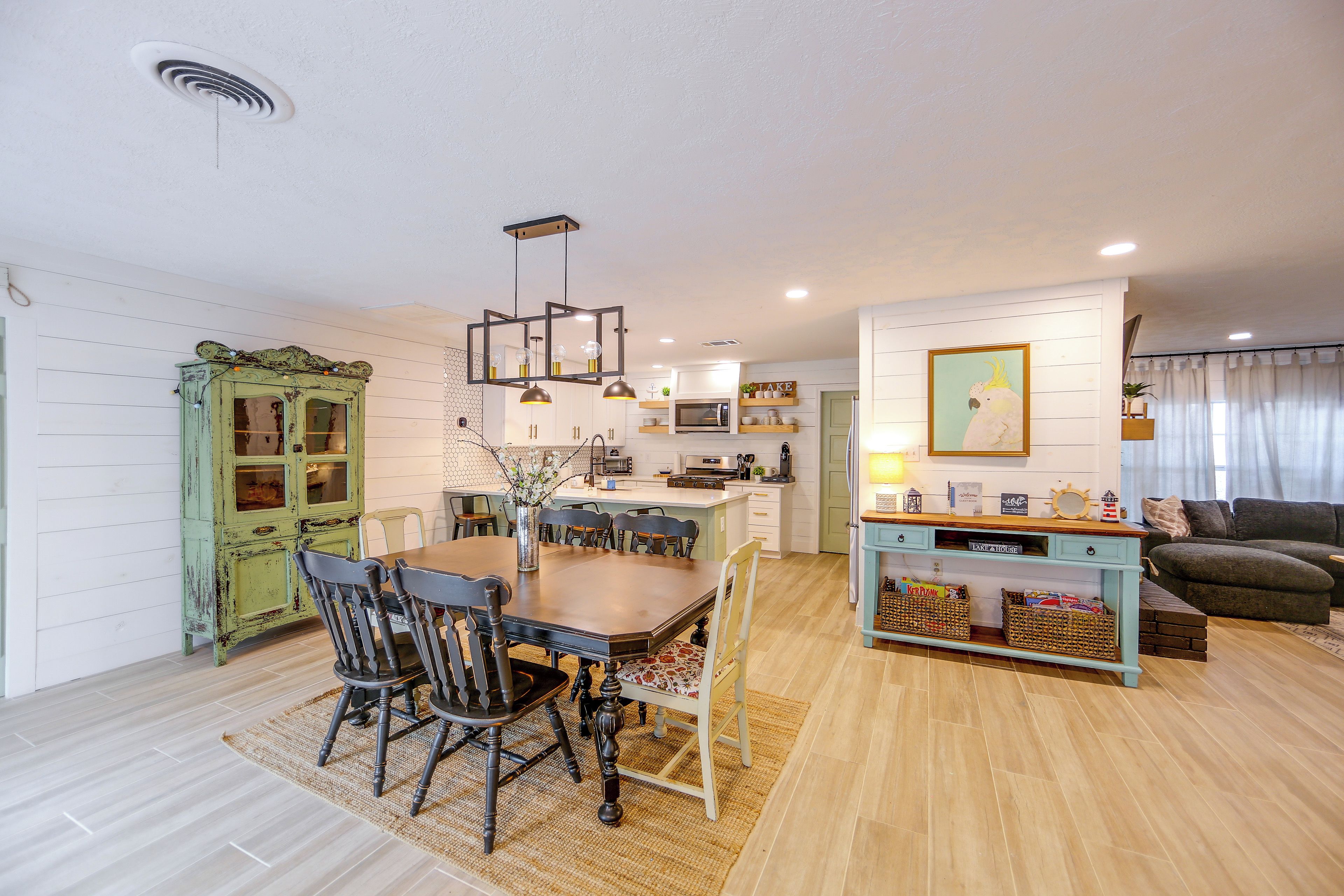 Eine moderne Küche mit Essbereich, Holzboden und einem gemütlichen Wohnraum mit Sofa und Dekoration.