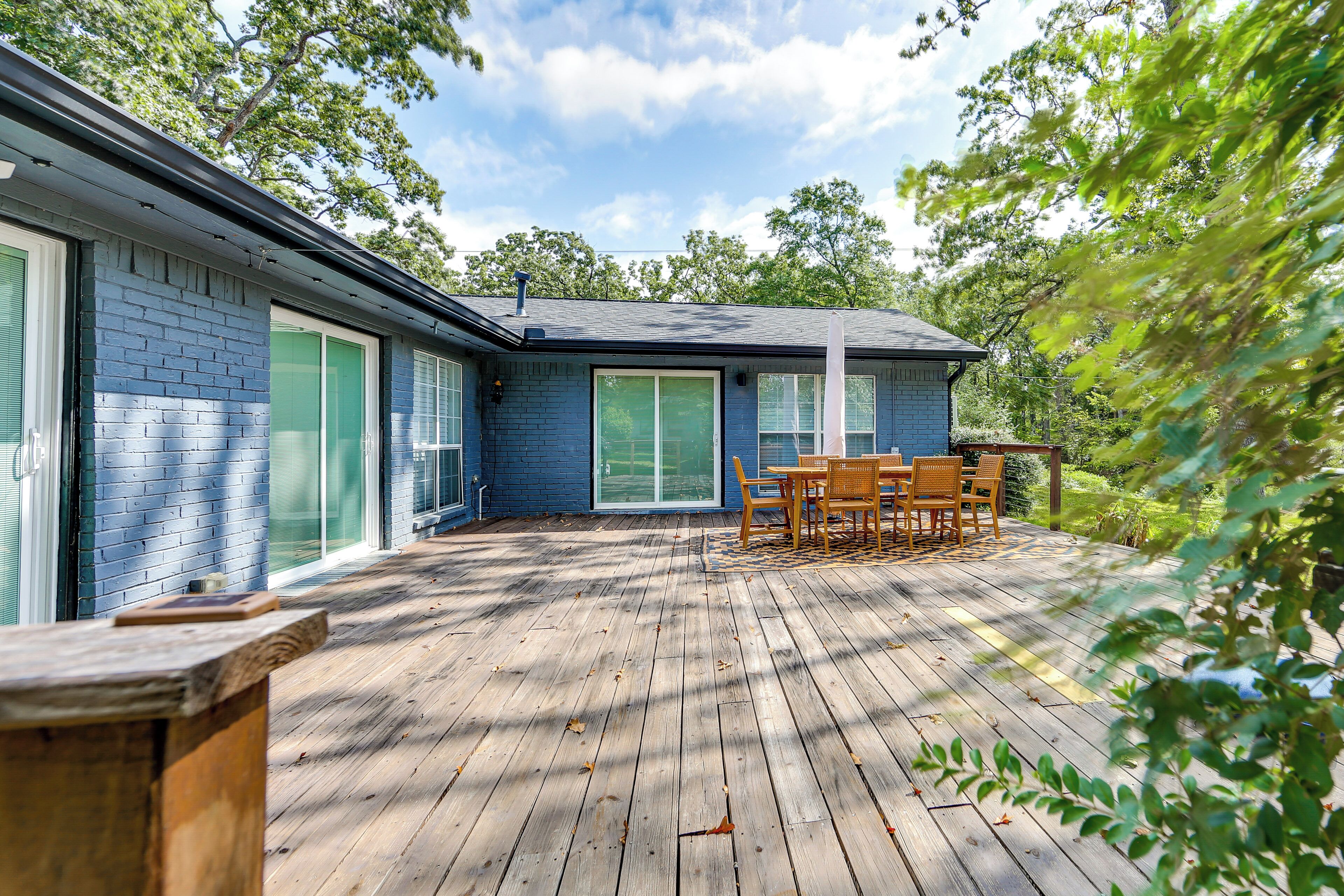 A blue house with a deck, a table, and chairs.