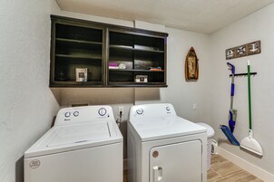 Un área de lavandería con dos lavadoras de carga frontal, una ventana arriba y un tendedero de pared.