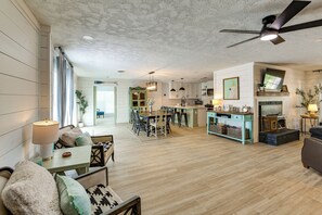 A spacious living area with a dining table, chairs, and a sofa. There is a kitchen area with modern appliances and a dining table. The room has wooden flooring and a ceiling fan. - Dock & Golf at Cedar Creek! 'shoreline Retreat' (Malakoff)