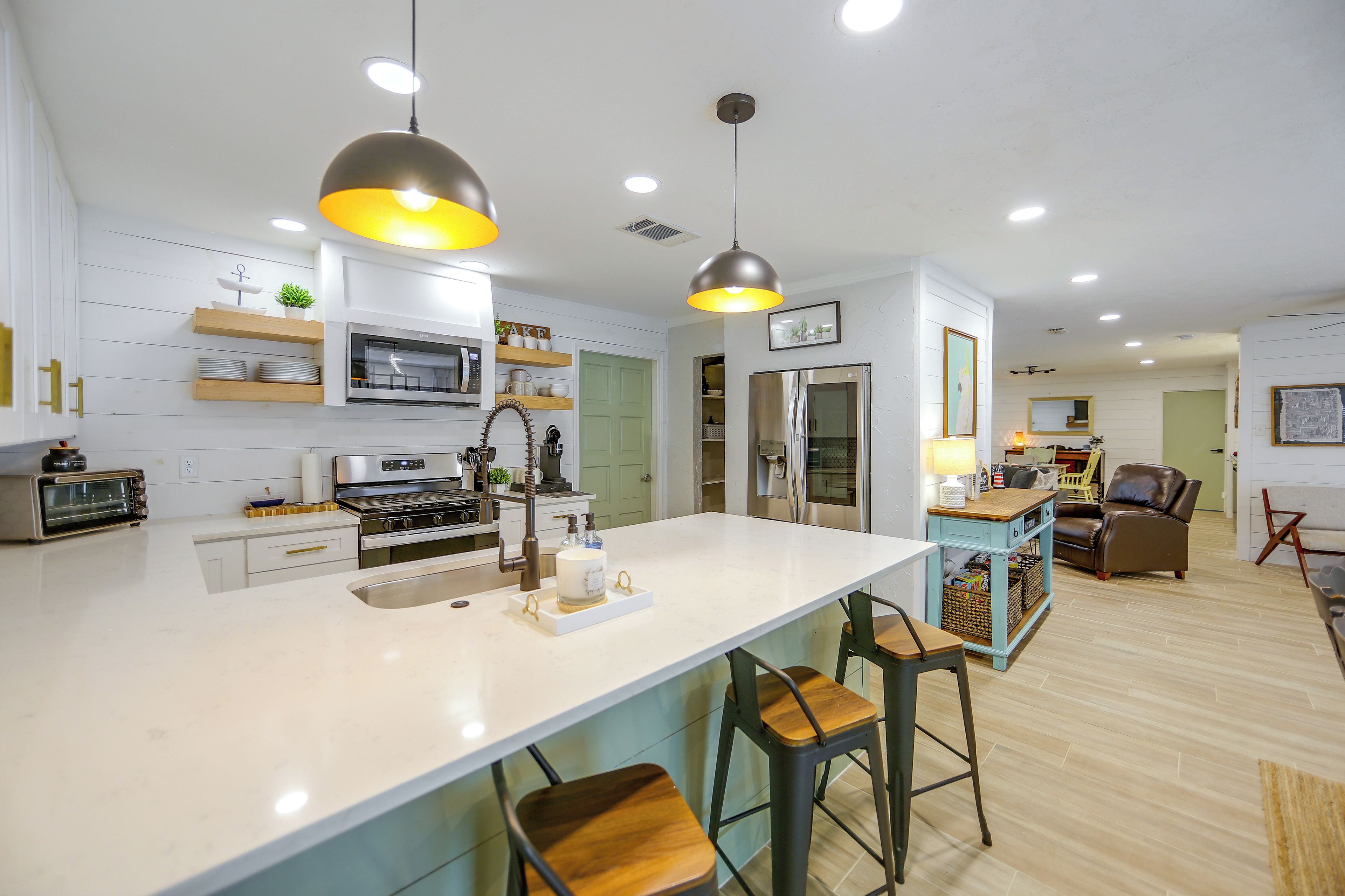 A modern kitchen with a central island, bar stools, and a dining area with a table and chairs.