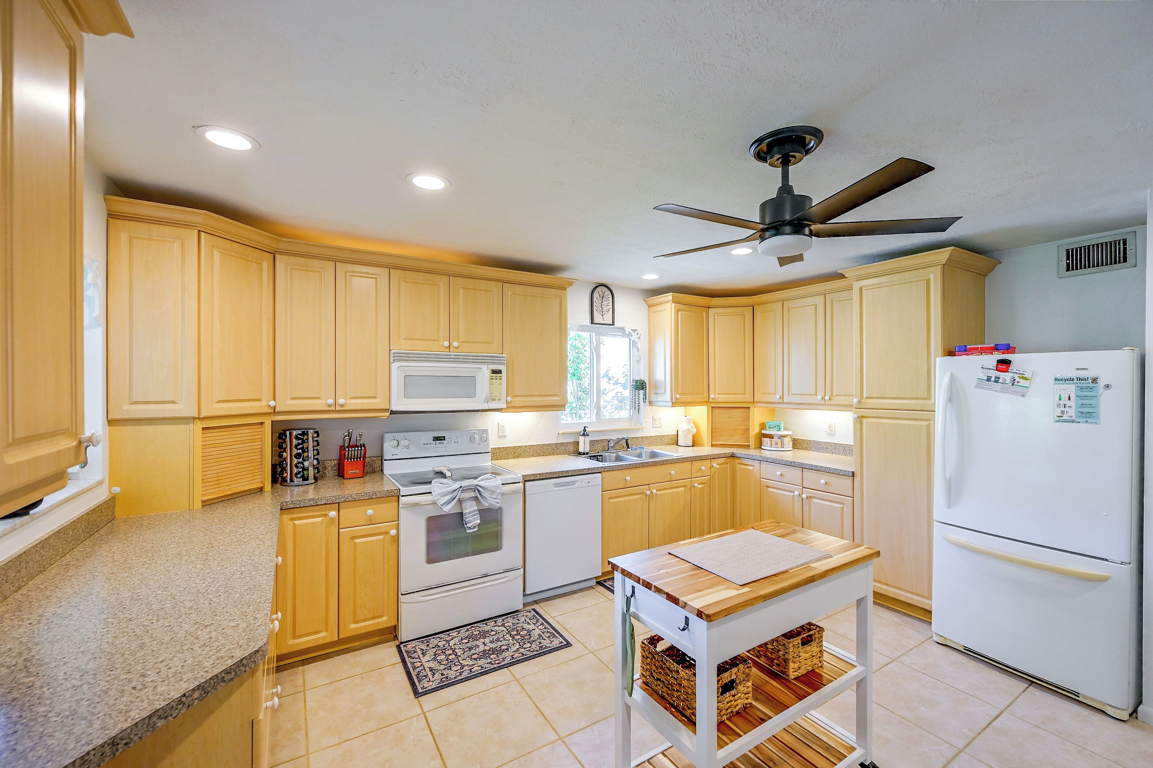 A kitchen with wooden cabinets, a microwave, stove, and a refrigerator.