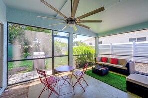 A sunlit patio with a ceiling fan, a table, red chairs, and a sofa with red cushions. - 1 Mi to Vanderbilt Beach! Group-friendly Getaway (Naples)