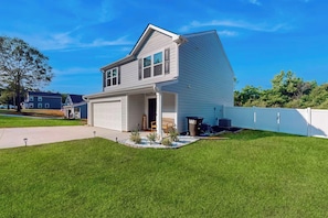 A two-story house with a garage, a front porch, and a well-maintained lawn.