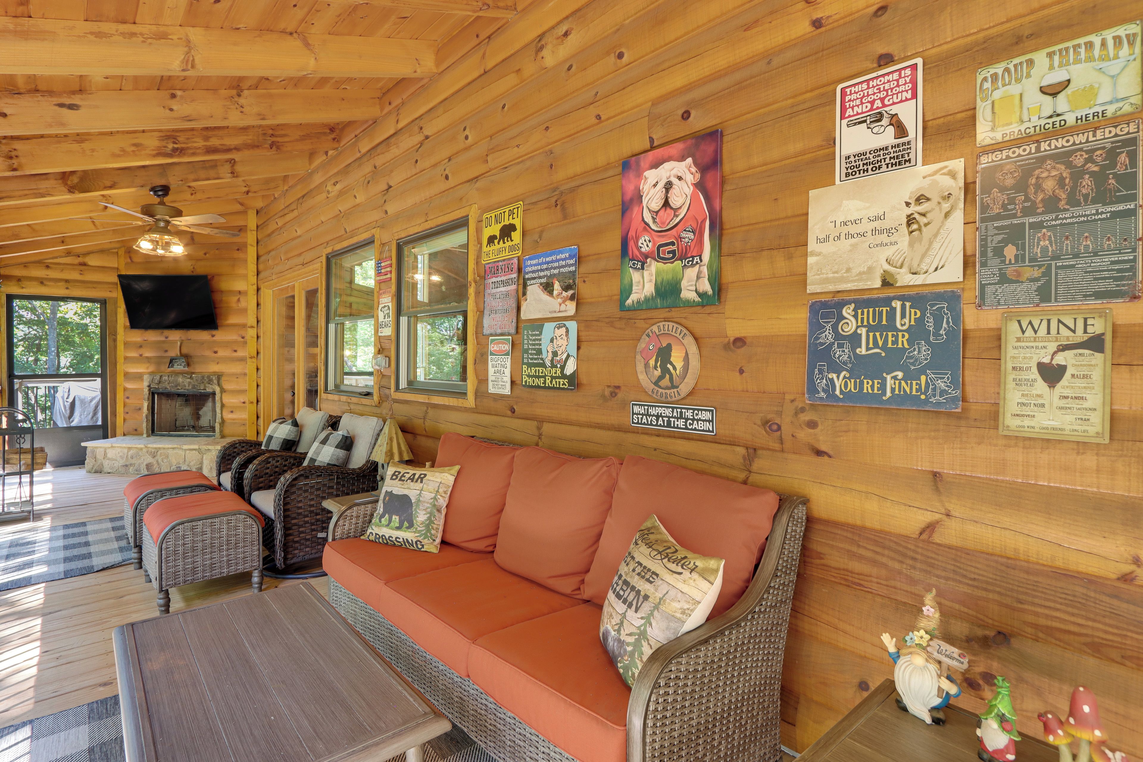 Interior de una cabaña con detalles de madera, un sofá, chimenea y diversas decoraciones en las paredes, incluyendo letreros y carteles.