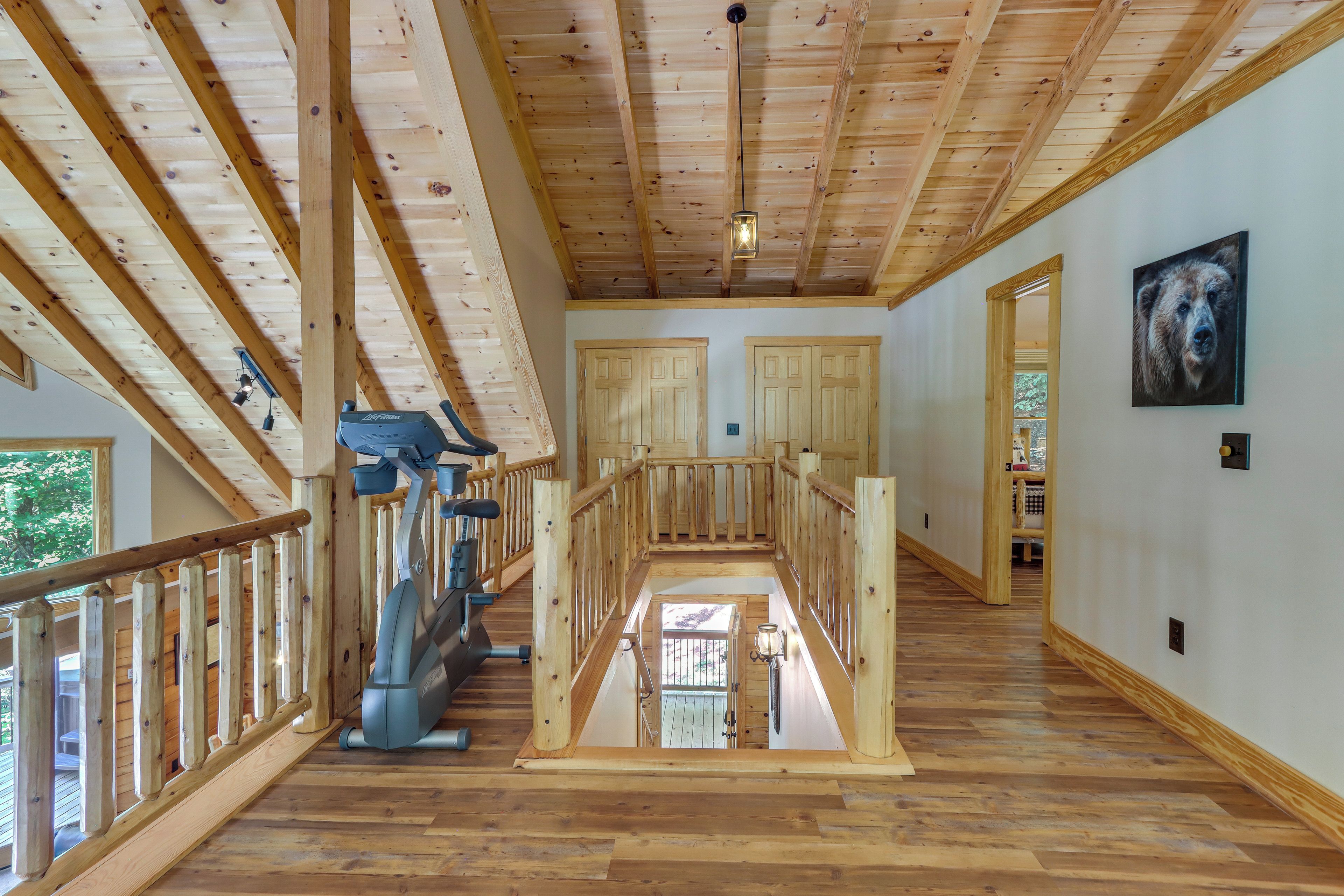 Un amplio espacio interior con pisos de madera, una escalera central y un techo con vigas a la vista.