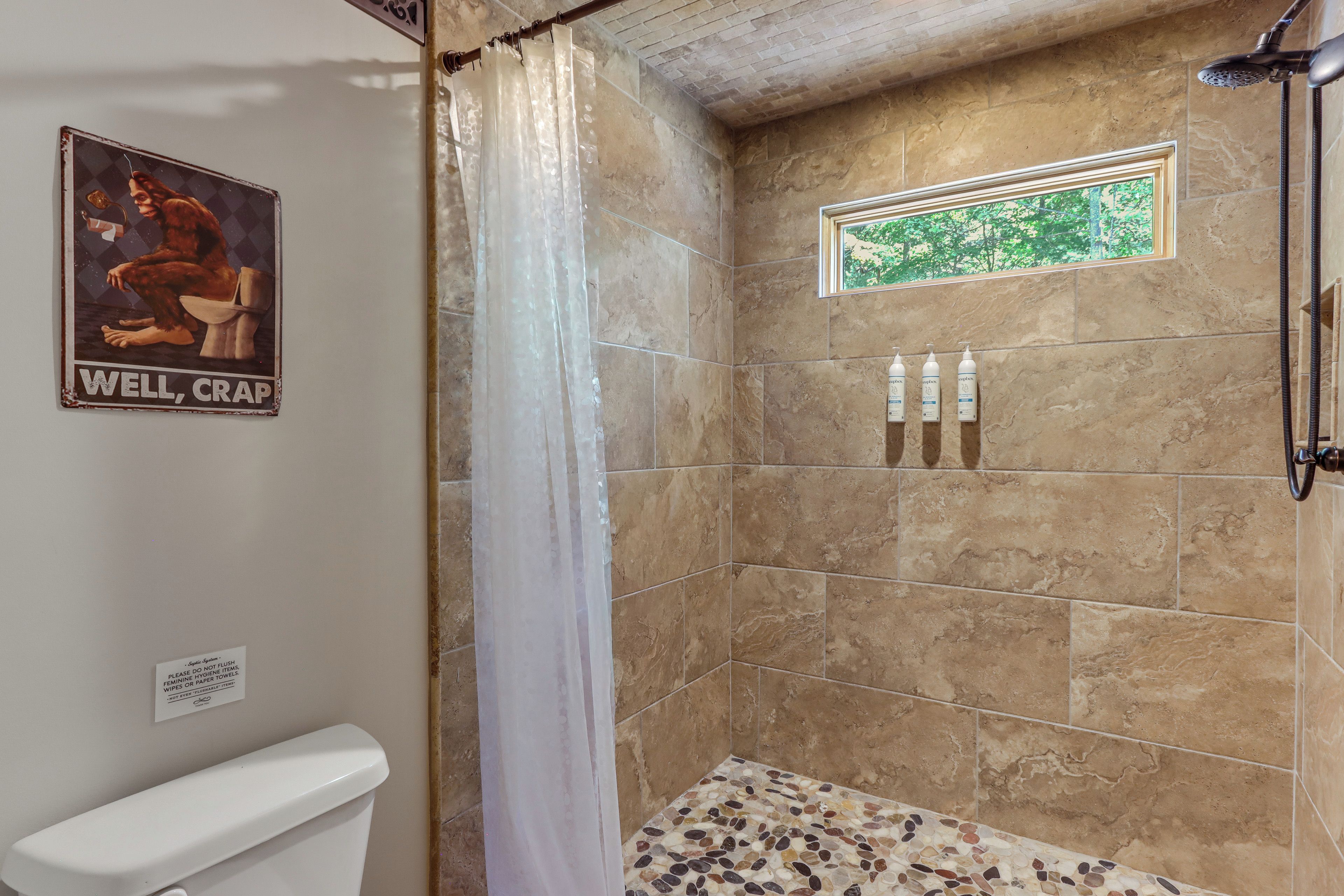 A shower with a glass door, a window, and a tiled floor.
