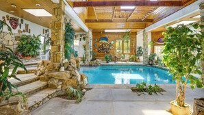 An indoor swimming pool with stone walls and wooden beams, surrounded by various plants and decorative items. - Family Retreat Ready! 'castlewood Ranch' in Chico (Chico)