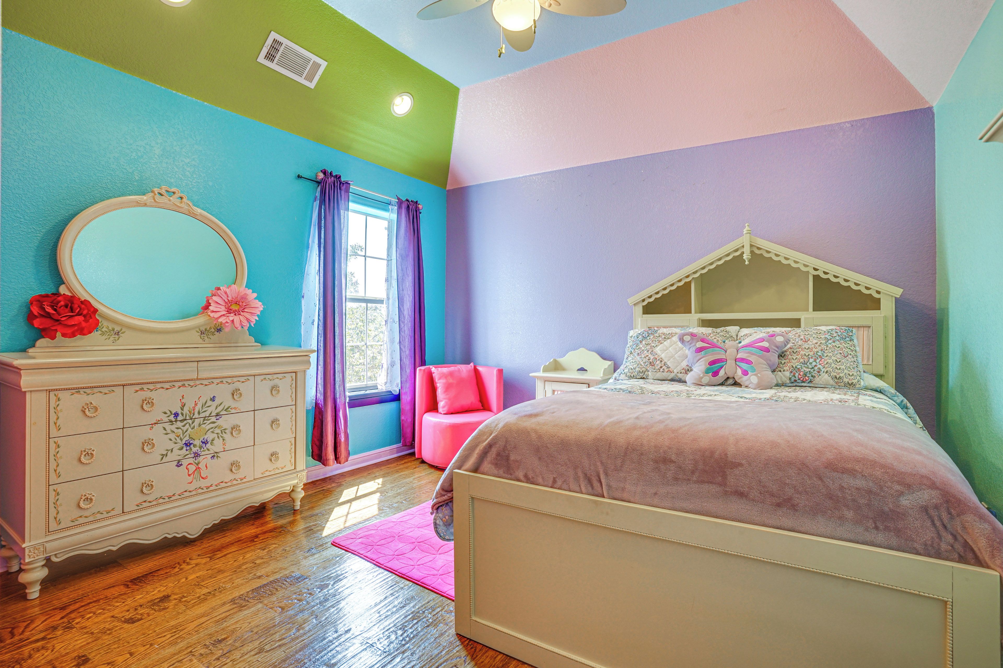 A bedroom with a bed, dresser, and a window with curtains.