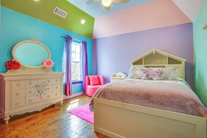 A bedroom with a bed, dresser, and a window with curtains.