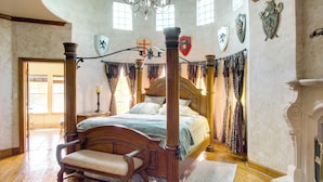 Una cama con dosel, un banco de madera y una chimenea.