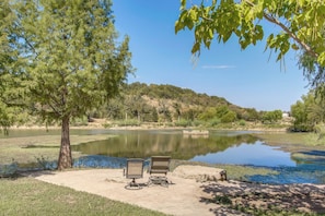 A tranquil lakeside setting with two chairs and a table, surrounded by trees and a hill in the background. - Family Retreat Ready! 'castlewood Ranch' in Chico (Chico)